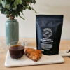 Gjengangern malt kaffe står på et bord med en kaffekopp og scones
